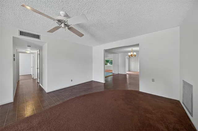 a view of an empty room with wooden floor and a ceiling fan