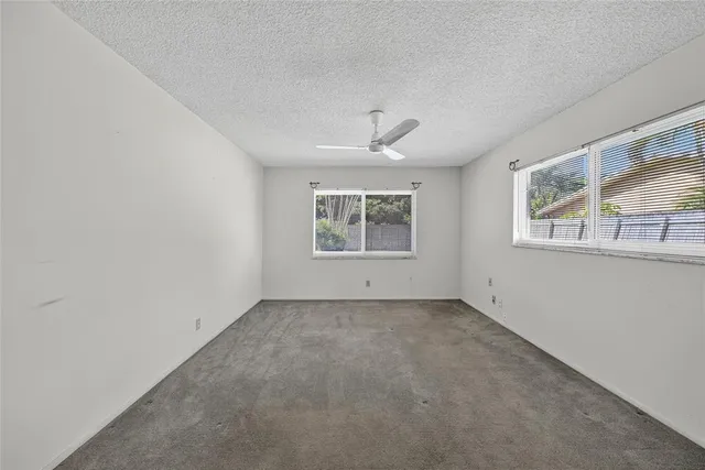 an empty room with windows and chandelier fan