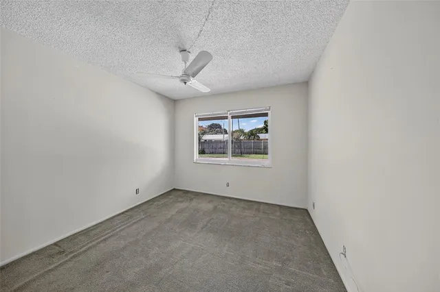 an empty room with a window and ceiling fan