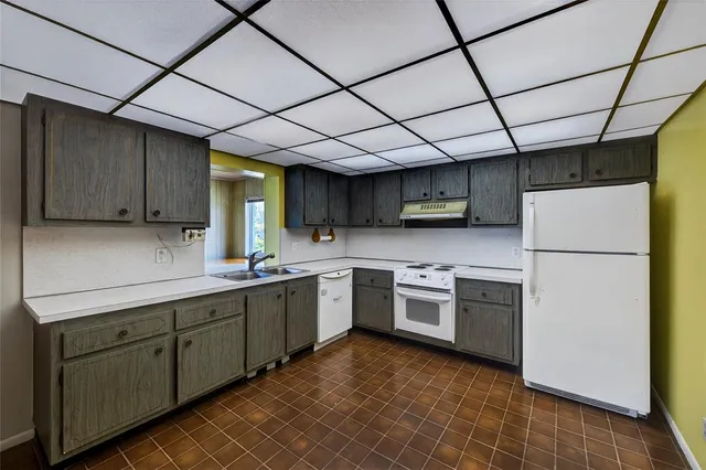 a kitchen with stainless steel appliances granite countertop a sink a stove a refrigerator cabinets and a counter top space