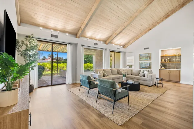 a living room with furniture large windows and wooden floor