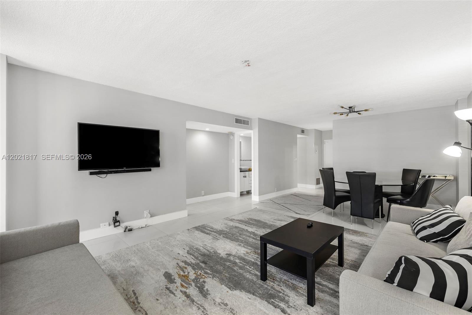 9511 Collins Avenue, Unit 1202 Surfside, FL 33154 - Photo 8 of 16 a living room with furniture and a flat screen tv