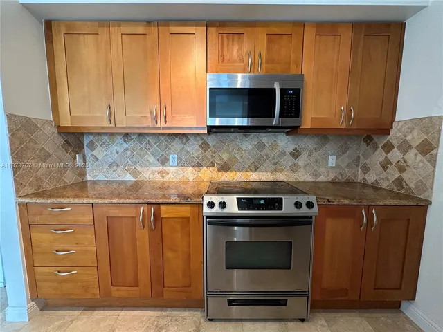 a kitchen with granite countertop wooden cabinets and stainless steel appliances