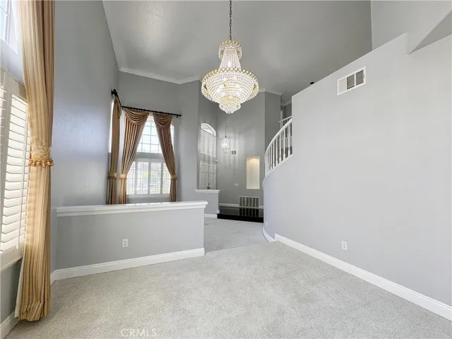 an empty room with stairs and a chandelier fan