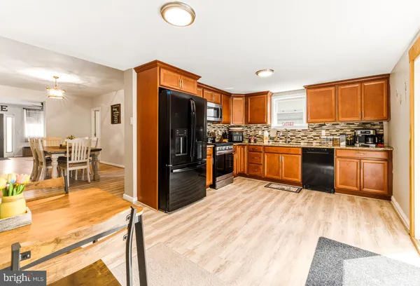 a kitchen with stainless steel appliances hardwood floor sink stove refrigerator and wooden cabinets