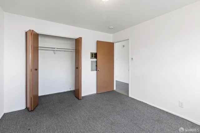 a view of an empty room with closet and a window