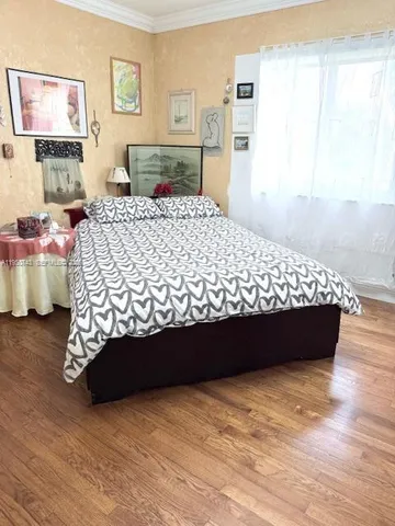 a bed sitting in a bedroom next to a window with wooden floor