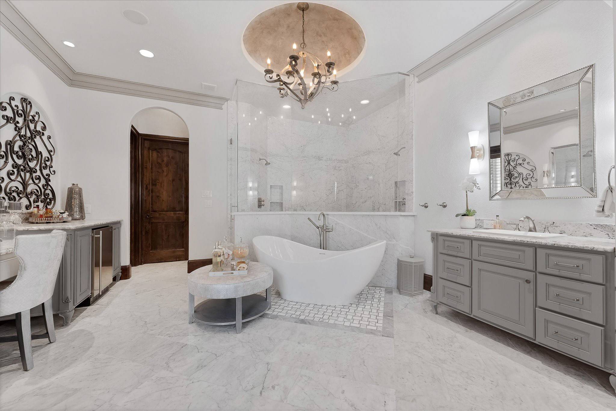 28322 Meadow Forest Magnolia, TX 77355 - Photo 21 of 50 Fully renovated Primary ensuite boosting Carrara marble walk-in steam shower with a frameless glass entry door, dual shower heads, designer polished nickel plumbing fixtures, built-in bench seats, and Carrara marble mosaic tile on the floor and ceiling. A freestanding soaking tub surrounded by Intricate tile pattern and Carrara marble flooring. An exterior door with custom wood shutters leads to the backyard and pool area.