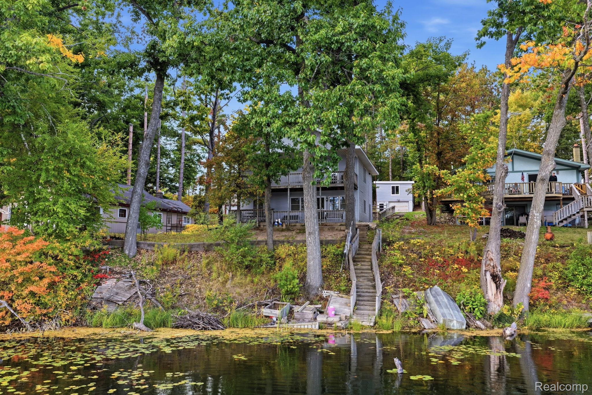 2259 Kassuba Road Gaylord, MI 49735 - Photo 3 of 46 Waterfront property featuring multiple structures, mature trees, and direct water access with a staircase