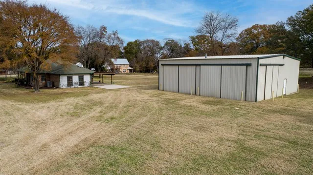 a view of a large white house with a yard and wooden fence