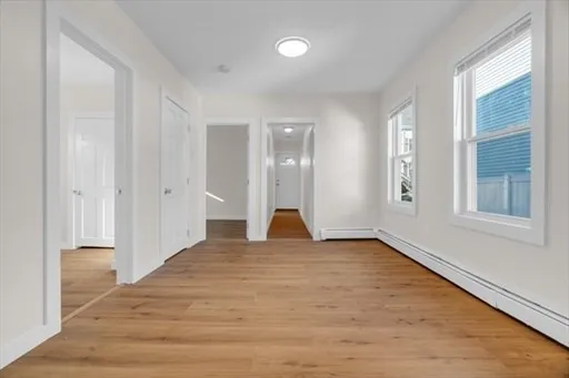 a view of empty room with wooden floor and fan
