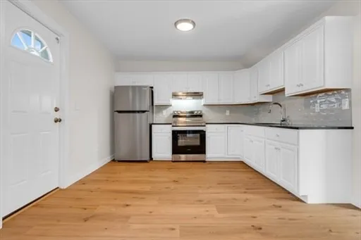 a kitchen with granite countertop white cabinets and stainless steel appliances