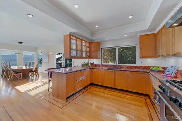 a kitchen with stainless steel appliances granite countertop a refrigerator a sink dishwasher a dining table and chairs with wooden floor