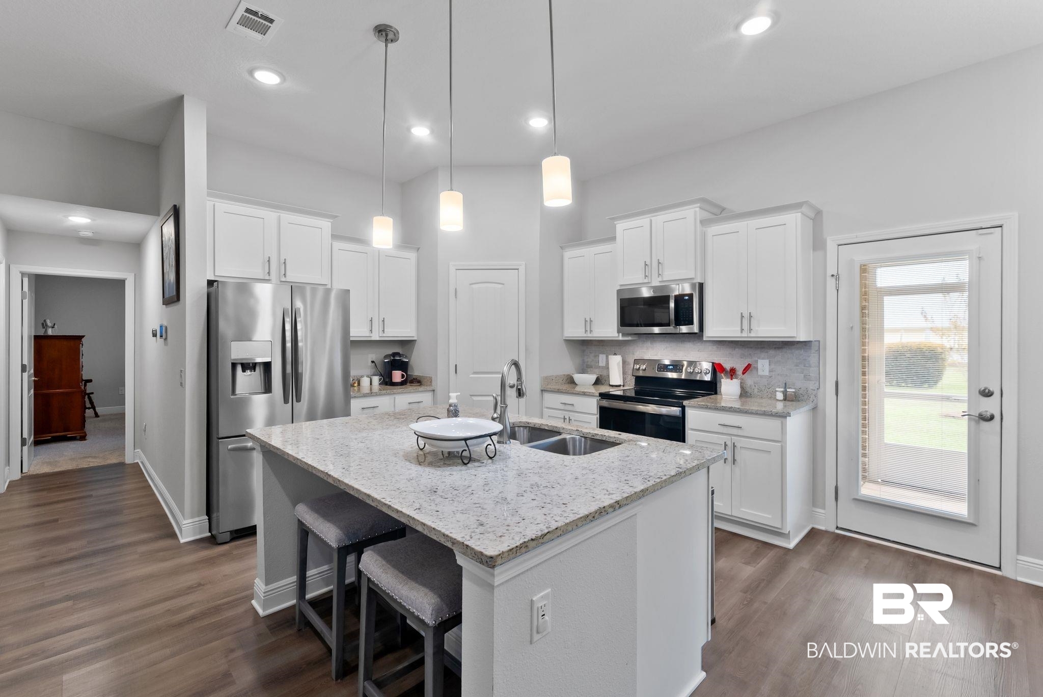 32868 Arbor Ridge Circle Lillian, AL 36549 - Photo 12 of 35 Kitchen featuring stainless steel appliances, white cabinets, a kitchen bar, an island with sink, and light stone countertops