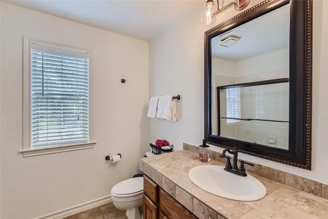 a bathroom with a granite countertop sink toilet and mirror