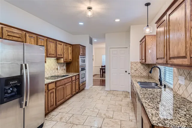 a large kitchen with granite countertop a sink refrigerator and cabinets