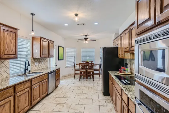 a large kitchen with stainless steel appliances kitchen island granite countertop a refrigerator and a stove top oven