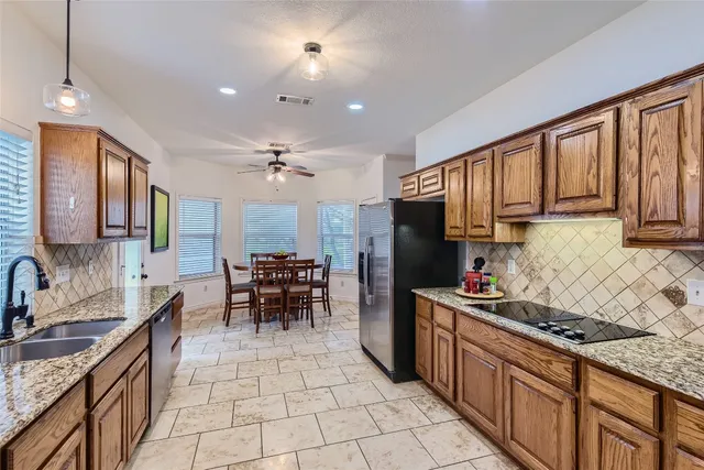 a kitchen with stainless steel appliances granite countertop a stove top oven a sink dishwasher a dining table and chairs with wooden floor