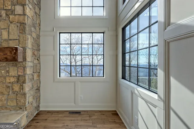 a view of an entryway with wooden floor leading to a furnished livingroom and windows