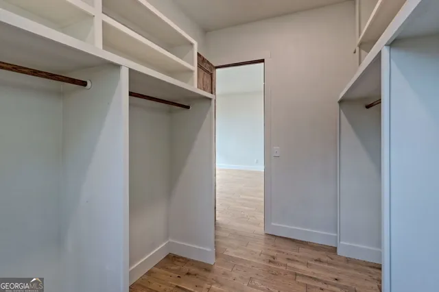 a view of an empty room with window and wooden floor