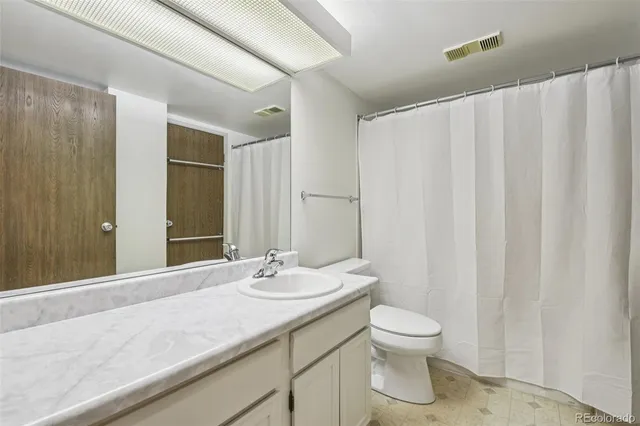 a bathroom with a granite countertop sink toilet a mirror and a vanity