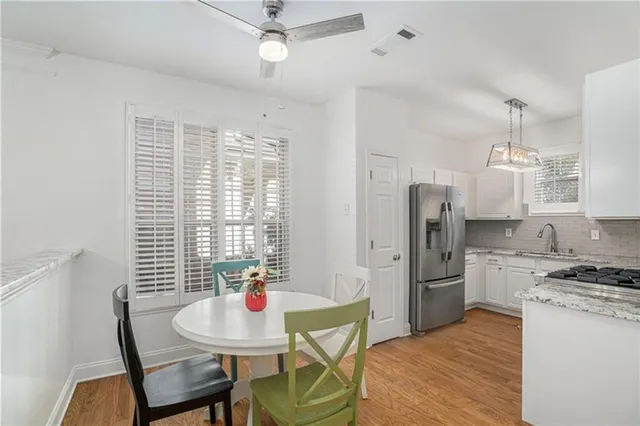 a kitchen with stainless steel appliances a dining table chairs and refrigerator