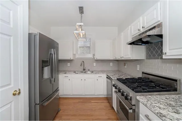 a kitchen with stainless steel appliances granite countertop a sink a stove a refrigerator and cabinets