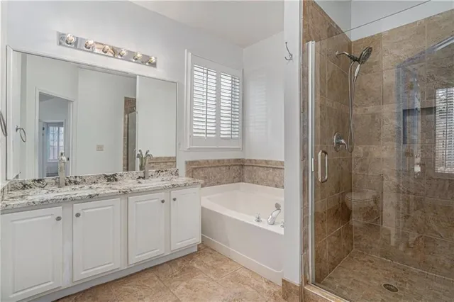 a bathroom with a granite countertop sink a mirror a bathtub and shower