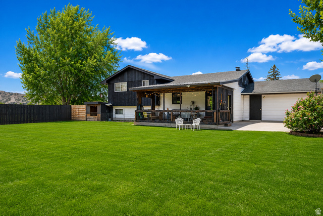 100 Third North Helper, UT 84526 - Photo 7 of 30 Expansive manicured lawn with a black privacy fence, mature trees, and a covered back patio