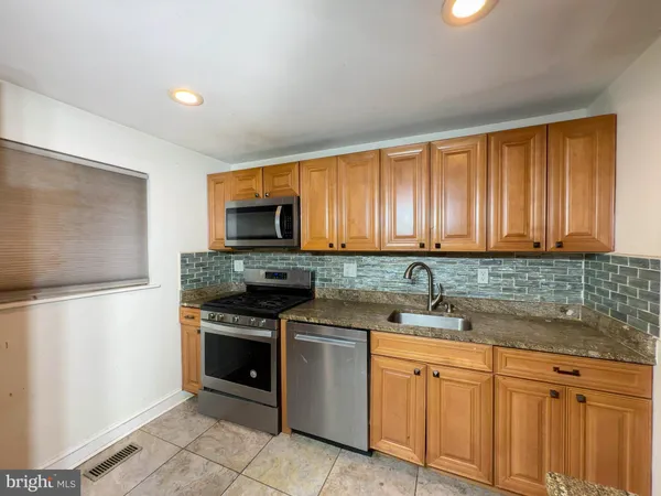 a kitchen with stainless steel appliances granite countertop a refrigerator sink and stove