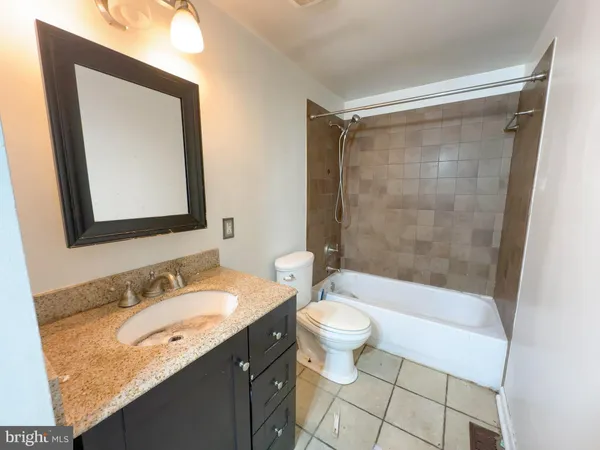 a bathroom with a granite countertop sink toilet mirror and bathtub