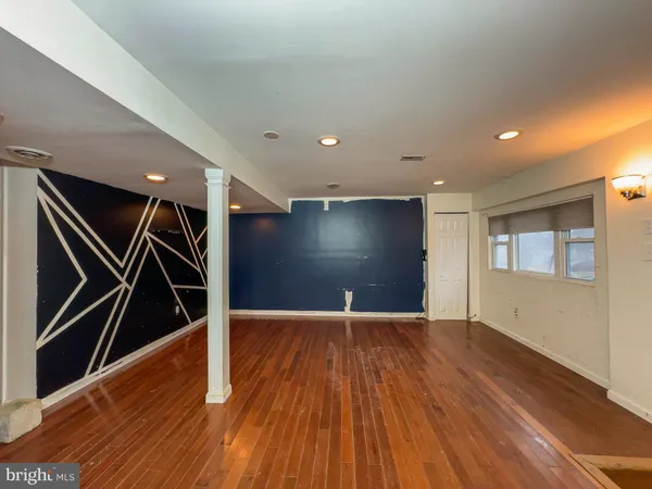 a view of an empty room with wooden floor and stairs