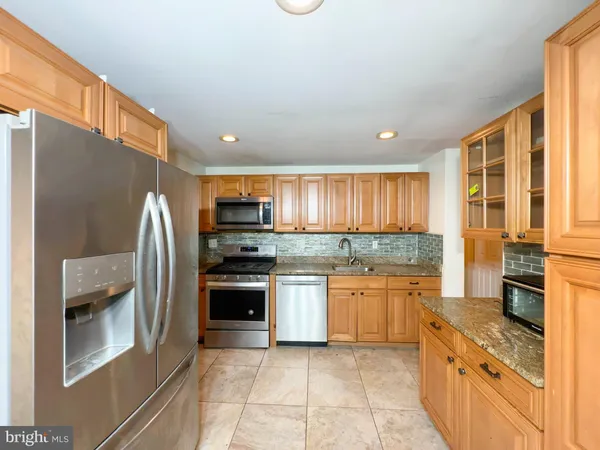 a kitchen with stainless steel appliances granite countertop a stove a sink and a refrigerator