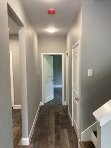 a view of a hallway with bathroom and wooden floor