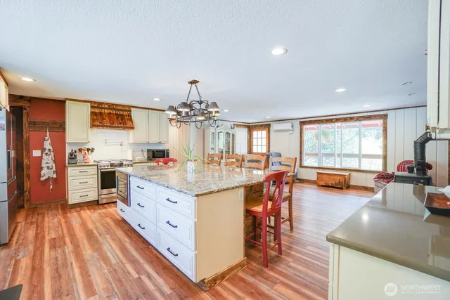 a large kitchen with stainless steel appliances granite countertop a lot of counter space and wooden floors