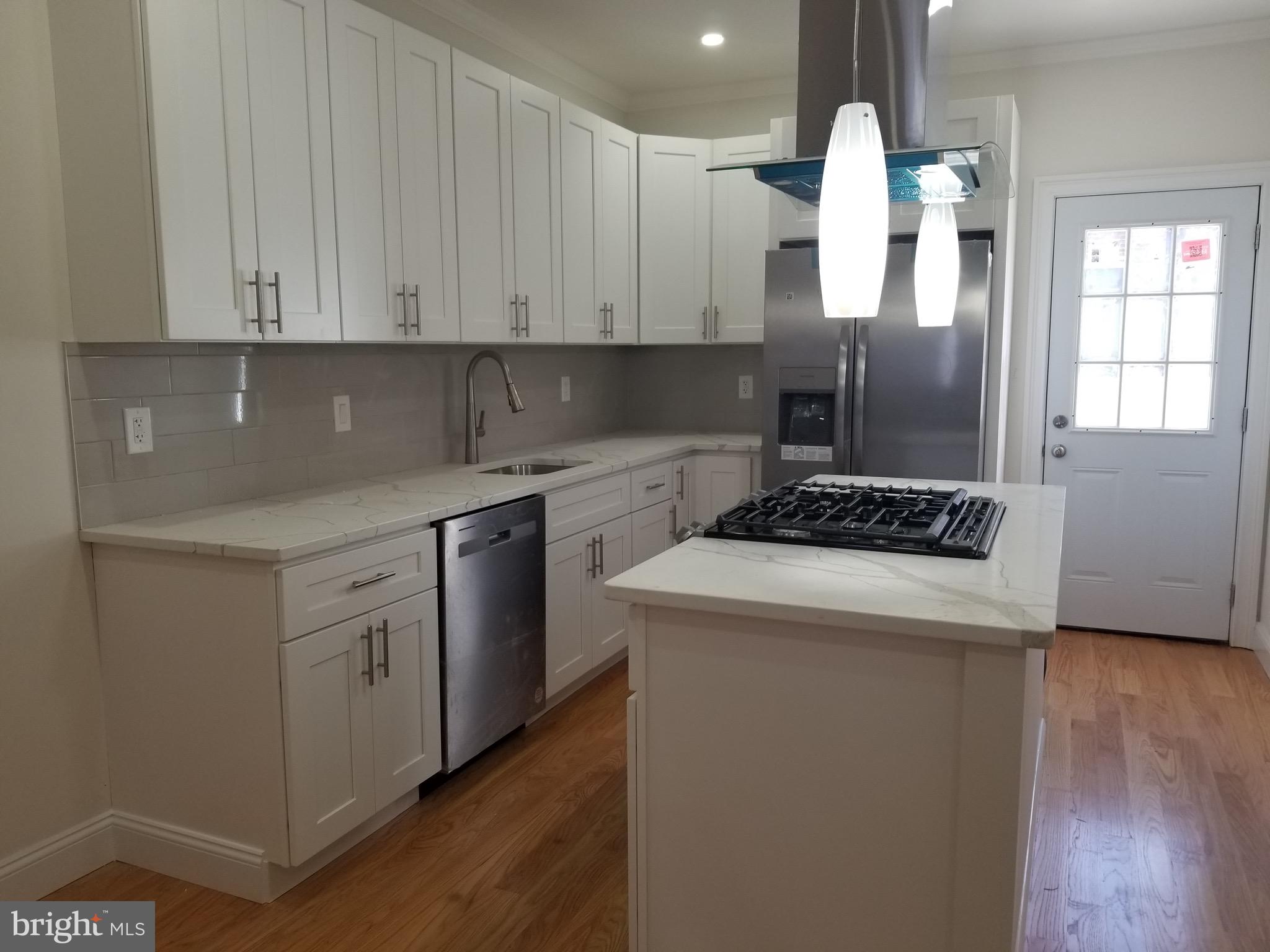 a kitchen with a white cabinets and wooden floor