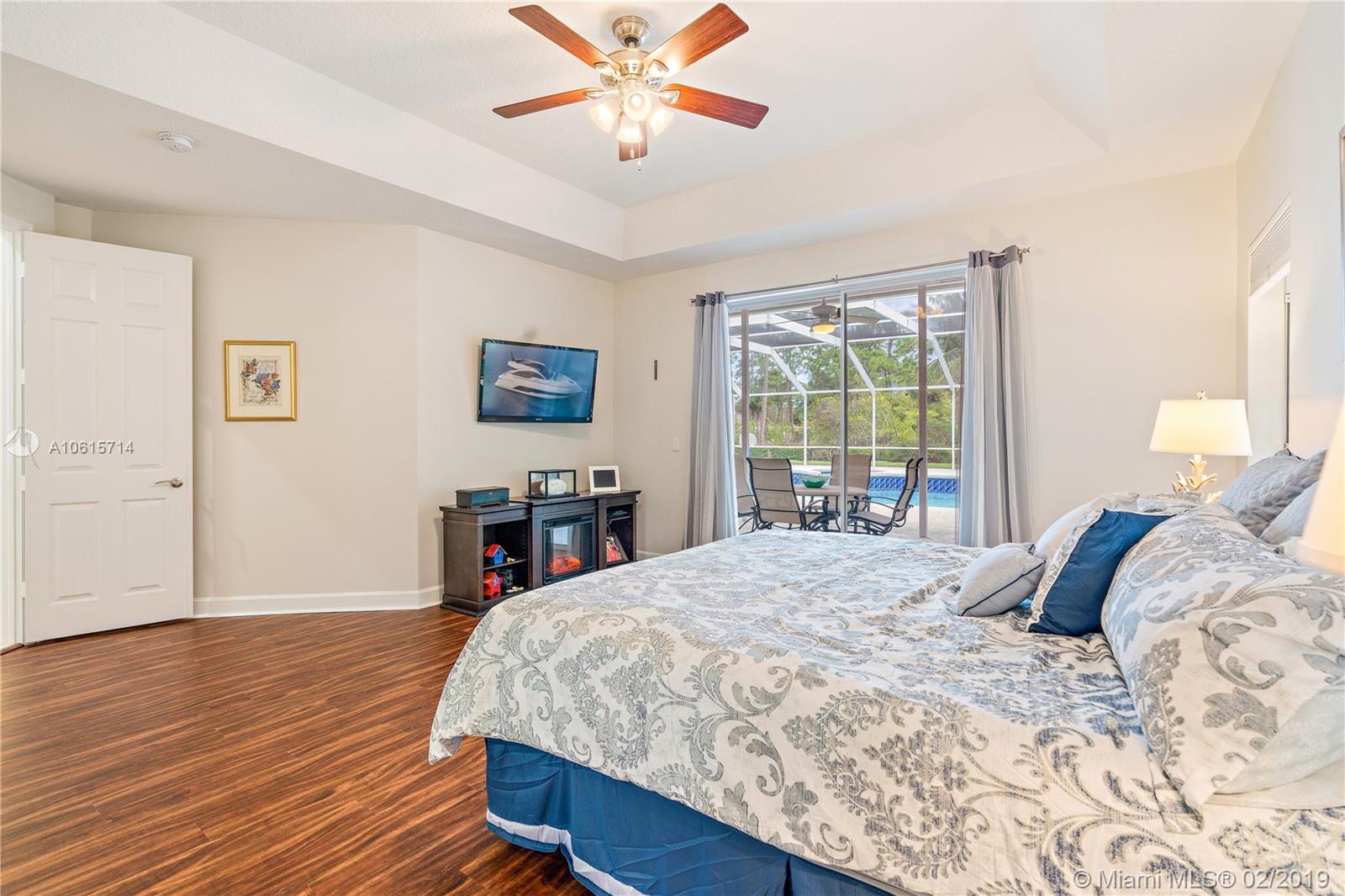 18897 Southeast Loxahatchee River Road Jupiter, FL 33458 - Photo 14 of 48 Master bedroom with slider doors that lead out to covered lanai and pool area.