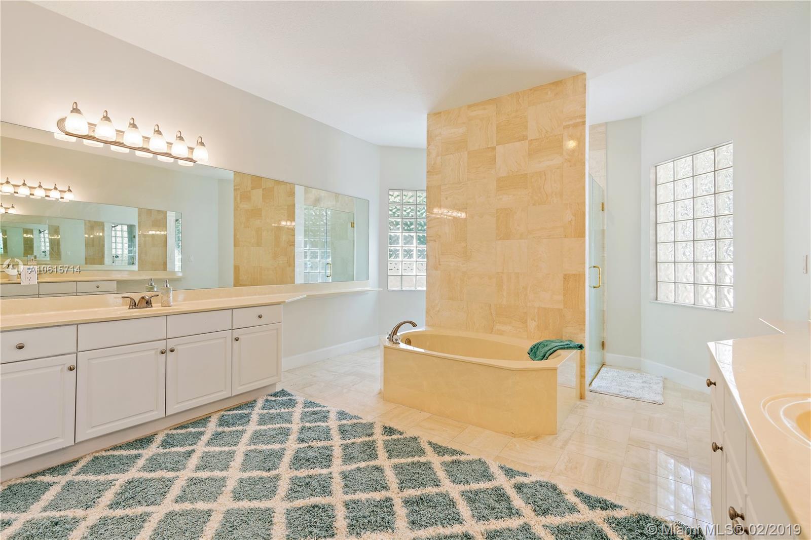 18897 Southeast Loxahatchee River Road Jupiter, FL 33458 - Photo 16 of 48 Master bathroom with marble floors dual sinks and vanities. Dual access shower behind the roman tub tile wall.