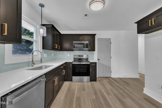 a kitchen with stainless steel appliances granite countertop a sink a stove and a refrigerator