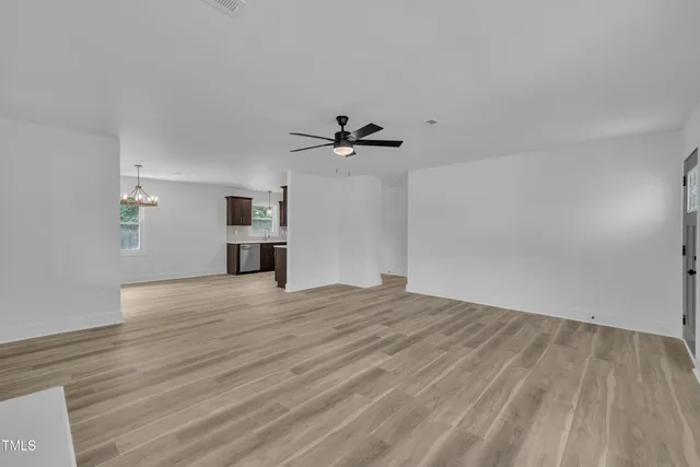 a view of empty room with wooden floor and ceiling fan