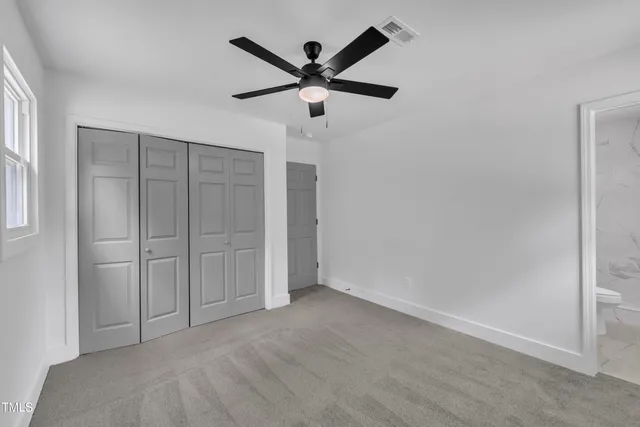 an empty room with closet and ceiling fan