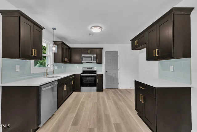 a large kitchen with stainless steel appliances wooden cabinets a stove and a refrigerator