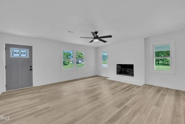 a view of an empty room with a window and a fireplace