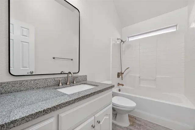 a bathroom with a granite countertop sink toilet and shower