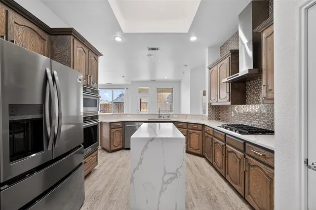 a kitchen with stainless steel appliances granite countertop a refrigerator a stove and a sink
