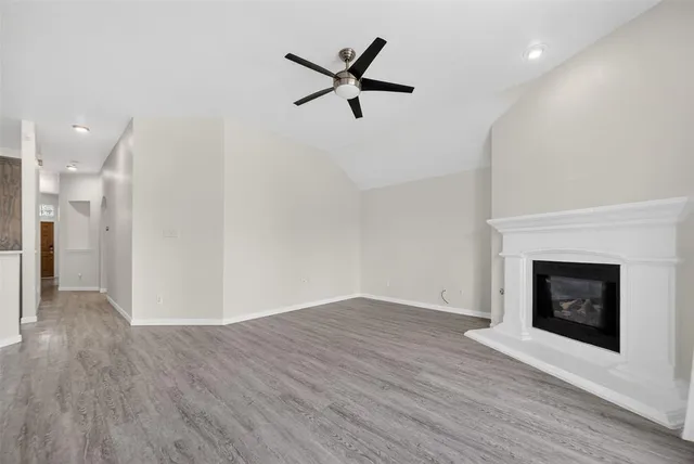 a view of an empty room with wooden floor and a fireplace