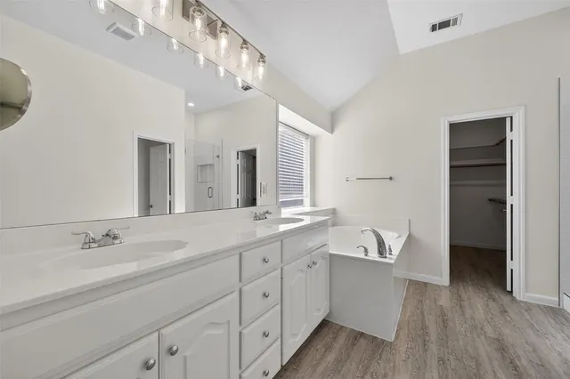 a spacious bathroom with a double vanity sink a mirror and a bathtub