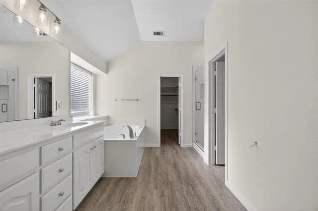 a spacious bathroom with a double vanity sink a large mirror and shower