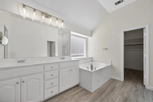 a spacious bathroom with a granite countertop sink mirror and bathtub