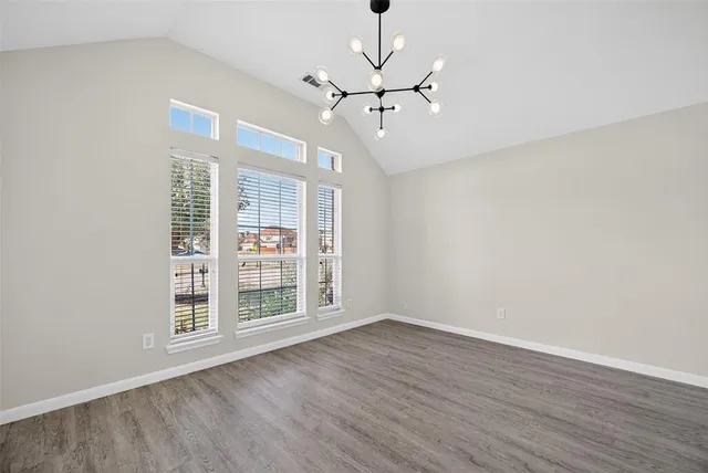 a view of an empty room with wooden floor fan and a window